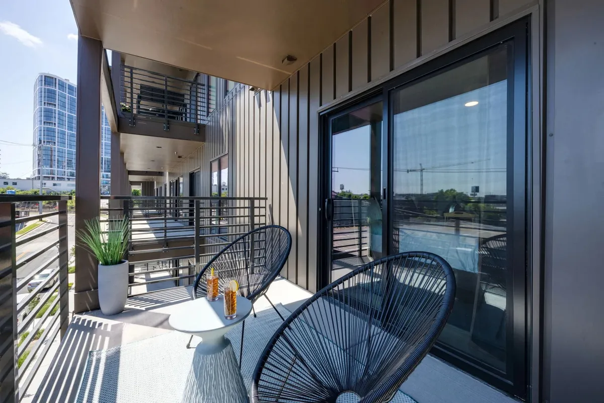A private balcony setup with comfortable chairs and a coffee table, offering sweeping urban views of the Nashville skyline. It's a tranquil outdoor space ideal for relaxing mornings or stargazing nights.