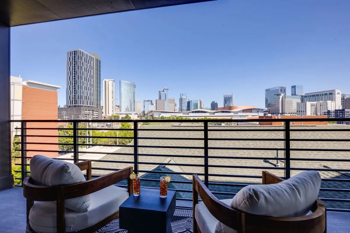 A tranquil balcony scene featuring two stylish chairs and a small table with cocktails, perfectly positioned to take in sweeping city views. The ambiance is intimate and serene, ideal for quiet reflection or special gatherings.