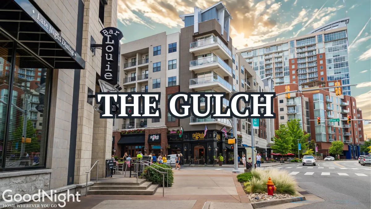 An exterior view of The Gulch area, showcasing the Bar Louie sign, modern buildings, and an inviting outdoor seating area. The atmosphere is lively and social, with hints of local dining and boutique exploration.