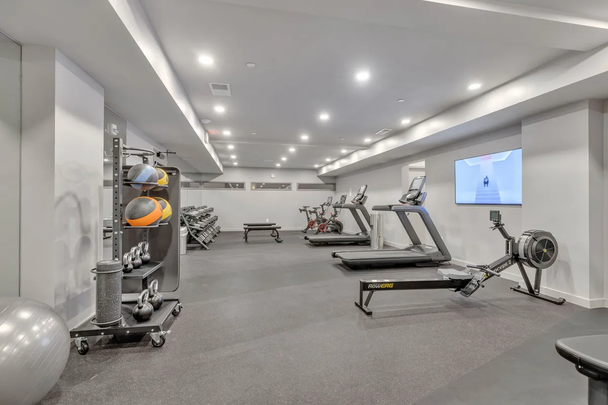 A modern, well-equipped on-site gym featuring treadmills, rowing machine, exercise bikes, dumbbells, and an exercise ball. The space is bright and motivating, ideal for maintaining a wellness routine while traveling.